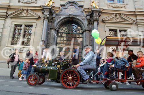 Eine nostalgische Dampflok-Eisenbahn mit begeisterten Kindern fährt vor Zürich's Rathaus vor am Züri-Multimobil-Tag