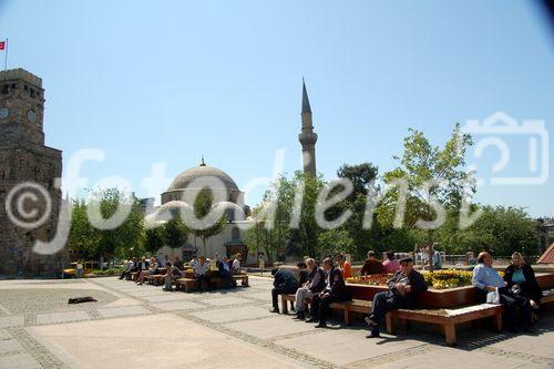 Das Wahrzeichen Antalyas ist das Minarett der Yivli-Minare-Moschee, das im 13. Jahrhundert unter dem seldschukischen Sultan Kai Kobad I. erbaut wurde.
Davor ein prächtiger Park mit vielen Personen, Menschen, die da sitzen und 
rumschauen. Das 38 Meter hohe Minarett (2) 