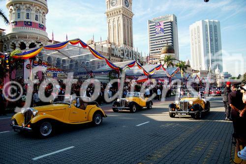 50 Jahre Merdeka Unabhängeits-Parade am 31. August 2007 in K uala Lumpur mit zahlreichen ausländischen Staatsgästen, vielen Staatschefs und Regierungspräsidenten aller asiatischen Länder sowie Abgesandte, Diplomaten von den USA, von UK Britischem Königreich. Veteranen-Parade mit Oldtimer-Mobilen fahren vor.
Kolonialismus, Unabhängigkeit, Islam, Staatsreligion. Medienspektakel, Journalisten, 
Sicherheitsleute, Beamte, Regierung, Besucher, Militärparade, Islam, Staatsreligion,
mit zahlreichen asiatische Länder-Staatschefs und Regierungspräsenten zu Gast 

Veteran-Parade with oldtimer  in front of the tribune with all the asian premier-ministers and diplomats from all over the world. at the 50 Years Merdeka-Parade in Kuala Lupur at 31st of august 2007. Celebration of 50 years nation-building and freedom from the british empire colonialism in a malay-muslim, chinese, indian mixed society. The Tribune in front of the parliament house with the invited asian presidents and representatives, diplomats from UK and USA as well as from many more countres. Mediaspectakel with thousands of journalist, TV-Stations and media-representatives around the world covering this big malaysian event of history
