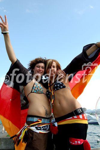 Zwei Deutsche Fussballfan-Frauen posieren freudig wie Engel vor dem TV-Monitor im Zürichsee. German female footballfans posing in front of the TV-Monitor at the lake Zürich.