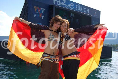 Zwei Deutsche Fussballfan-Frauen posieren freudig wie Engel vor dem TV-Monitor im Zürichsee. German female footballfans posing in front of the TV-Monitor at the lake Zürich.