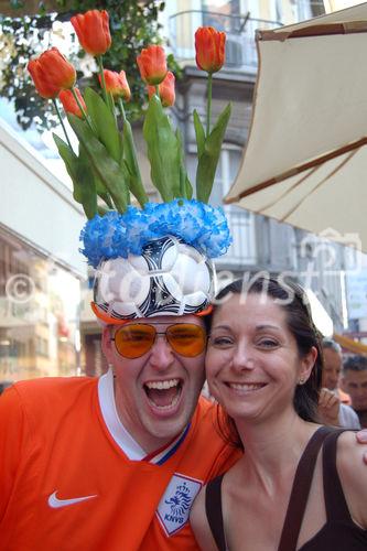 Holländischer Fussballfan mit Tulpen-Hut und orangem Spieler-Trikot umarmt Baslerin in der Fanzone. Dutch footballfan with flower-hut-decoration in Basel is hugging a swiss girl from Basel at the Euro 2008 Uefa-Sportevent