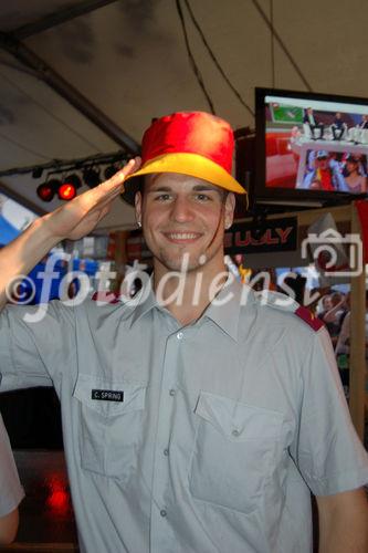 Schweizer Soldat mit Deutschem Fanhut und geschminktem Gesicht  in Achtungsstellung in der Fanzone von Zürich. Swiss soldier with german hut and painted face in Zürich's Fanzone