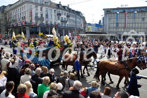 Der traditionelle Festumzug der Zürcher Zünfte mit ihren Kutschen, Pferden und Musikern zieht am Paradeplatz vorbei. The traditional Sechseläuten-Parade is crossing with horses the Paradeplatz  in Zürich