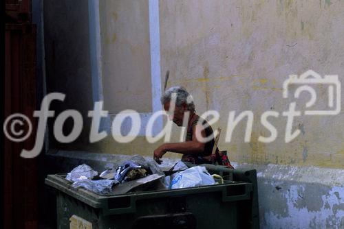 Eine hungrige Cubanerin durchwühlt einen Abfallcontainer in Havanna. A hungry cuban women searches for food in a garbage-container in Havanna