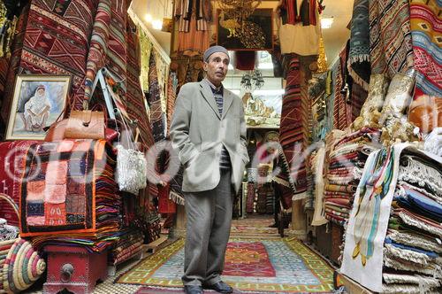 Teppichhändler wartet in seinem Souk in der Medina von Tunis auf bessere Zeiten und gute Geschäfte mit Touristen und Einheimischen