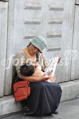 Peruanerin stillt ihr jüngstes Kind auf offener Strasse während dem Caliente-Festival. Young Indio-women is breatfeeding her baby on the Street in Zürich during the Caliente-Festival