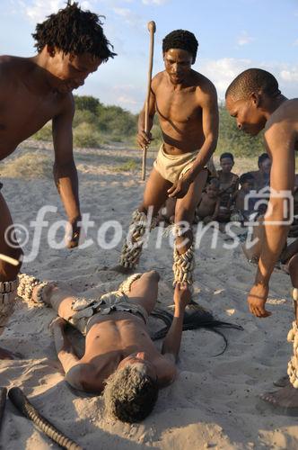 Bushmen-Rituale: Spielerische Jagd auf Wildtiere. Naro-Bushmen - near Ghanzi at GRassland Safari Lodge in the Central Kalahari - showing how the would hunt an animal and kill it with the stick and knive.