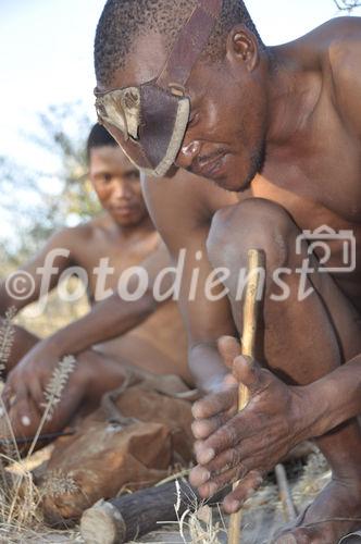 Bushmen makes fire with the wooden-sticks. mit den Feuer-Hölzern am Werk