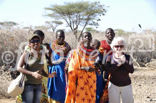 Samburu-Village-women with beautifull neckless beatwork and white LAdy. Samburu-Frauen mit wunderschönem Ohr- und Nackenschmuck aus bunten Glasperlen und europäische Frau tanzen zusammen