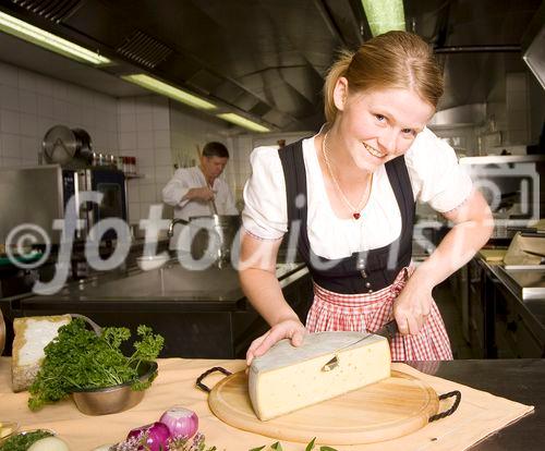 Genuss Region Kaiserwinkl Heumilchkäse - Rosmarie Geisler beim Schneiden von Plangger Bio-Käse, im Bildhintergrund: Alpenhotel-Chef Hans Geisler
Foto: Mühlanger
