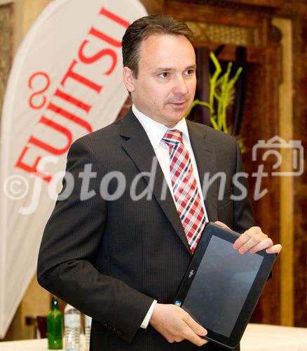 (C) fotodienst / Anna Rauchenberger  - Wien, 28.04.2011 – Fujitsu stellt mit 'Managed Smartphone' weltweit einen neuen Service zur Verfügung. Dank eines Pakets von gehosteten Mobile Professional-Lösungen können Unternehmen die Verwaltung ihrer Smartphones gezielt an Fujitsu auslagern und ihre betrieblichen Prozesse optimieren. FOTO: Johannes Baumgartner, Managing Director Fujitsu Österreich mit dem Multi-Touch-Gerät Fujitsu STLISTIC Q550