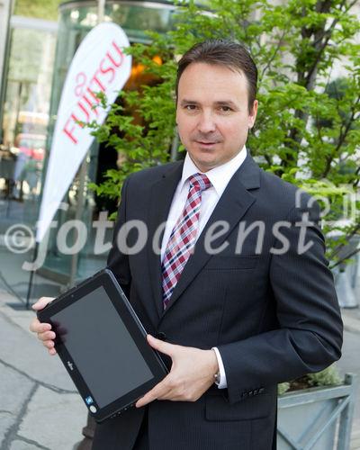 (C) fotodienst / Anna Rauchenberger  - Wien, 28.04.2011 – Fujitsu stellt mit 'Managed Smartphone' weltweit einen neuen Service zur Verfügung. Dank eines Pakets von gehosteten Mobile Professional-Lösungen können Unternehmen die Verwaltung ihrer Smartphones gezielt an Fujitsu auslagern und ihre betrieblichen Prozesse optimieren. FOTO: Johannes Baumgartner, Managing Director Fujitsu Österreich mit dem Multi-Touch-Gerät Fujitsu STLISTIC Q550