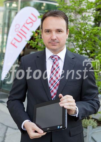 (C) fotodienst / Anna Rauchenberger  - Wien, 28.04.2011 – Fujitsu stellt mit 'Managed Smartphone' weltweit einen neuen Service zur Verfügung. Dank eines Pakets von gehosteten Mobile Professional-Lösungen können Unternehmen die Verwaltung ihrer Smartphones gezielt an Fujitsu auslagern und ihre betrieblichen Prozesse optimieren. FOTO: Johannes Baumgartner, Managing Director Fujitsu Österreich mit dem Multi-Touch-Gerät Fujitsu STLISTIC Q550