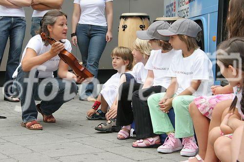 (C) fotodienst/Anna Rauchenberger - Wien 01.08.2006 - Ein bunt gestalteter Doppeldecker-Bus tourt durch Wien. Er bringt Musikinstrumente zum Anfassen und Ausprobieren in Schulen, Kindertagesstätten und andere Jugendeinrichtungen. Das klingende Mozart-Mobil soll Kinder und Jugendliche zum Musizieren animieren. FOTO: begeistete zukünftige Musiker und Musikpädagogin vor dem Mozart-Mobil.