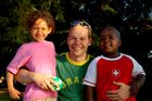 Ein junger Schweizer MAnn mit brasilianischem T-Shirt posiert mit einem jamaicanischen Mädchen und einem brasilianischen Einwanderer-Junge beim Fussball am Zürichseeufer. Integration fängt früh an und setzt die Bereitschaft der Schweizer Bevölkerung zur Annäherung an die Ausländer voraus