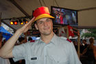 Schweizer Soldat mit deutschem Fanhut und in den NAtionalfarben Deutschands geschminktem Gesicht in Achtungsstellung in der Fanzone von Zürich. Swiss soldier with german hut and painted face with national colours of germany  in Zürich's Fanzone