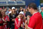 Weiblicher Fussballfan will Mann beim Fussballmatsch schminken und Frabe in sein Gesicht bringen. Female footballfan tries to put a make up on the mans face