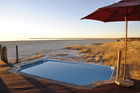 Entspannen Sie sich und geniessen Sie die herrliche Aussicht auf die Etosha-Salzpfanne vom Pool des Onkoshi Camps aus. Dieses Luxus-Lodge liegt nahe Namutomi und gehört zu den Namibia Wildlife Resorts. www.nwr.com.na.