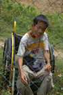 Behinderter Knabe in Vietnam beim Kriegsdenkmal des grausamen Massaker der US-Soldaten in Son My, wo 503 Personen, darunter viele Kleine Kinder starben.
Handicaped boy in a wheelchair near the war memorial Son My