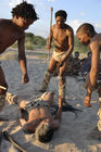 Bushmen-Rituale: Spielerische Jagd auf Wildtiere. Naro-Bushmen - near Ghanzi at GRassland Safari Lodge in the Central Kalahari - showing how the would hunt an animal and kill it with the stick and knive.