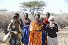 Samburu-Village-women with beautifull neckless beatwork and white LAdy. Samburu-Frauen mit wunderschönem Ohr- und Nackenschmuck aus bunten Glasperlen und europäische Frau tanzen zusammen